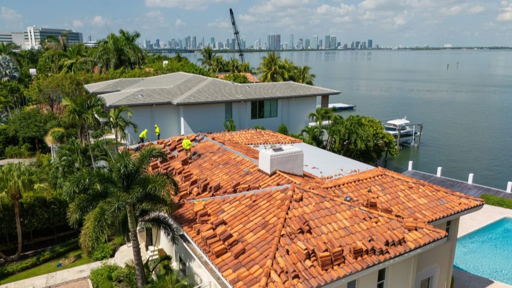 Luxury waterfront home with red tile roof and pool by Doga Construction.